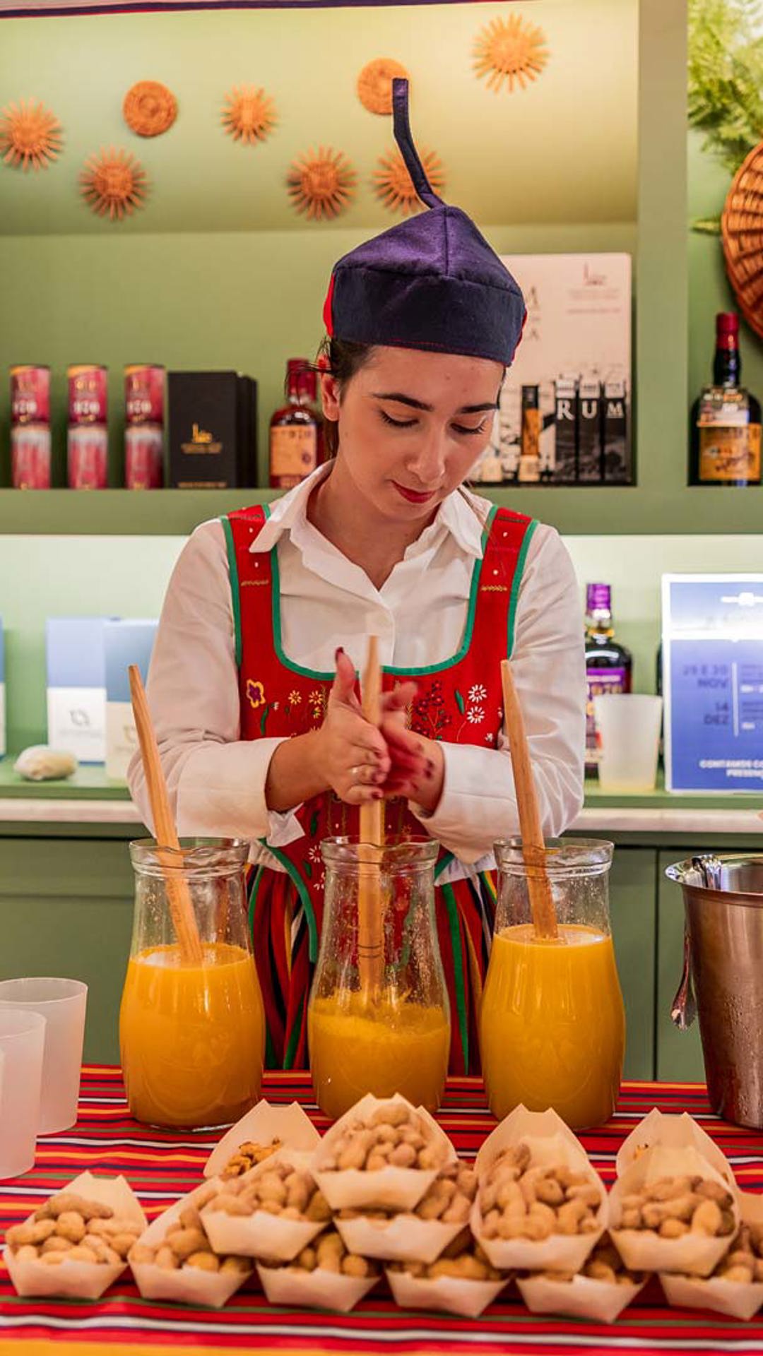 Event at the Madeira Tourism Office in Lisbon with a poncha stall and a woman serving.