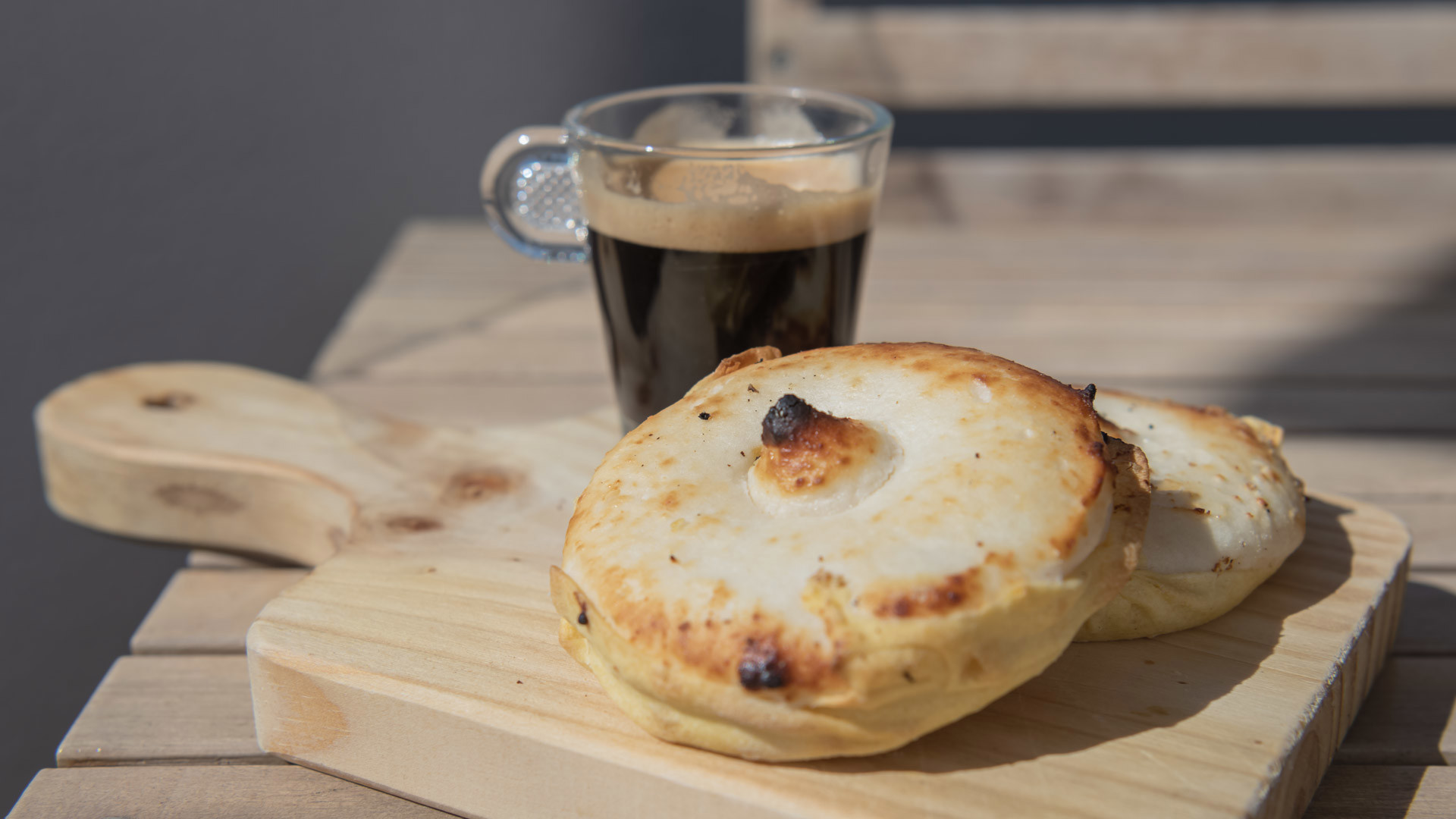 Duas queijadas servidas num prato acompanhadas por uma chávena de café.
