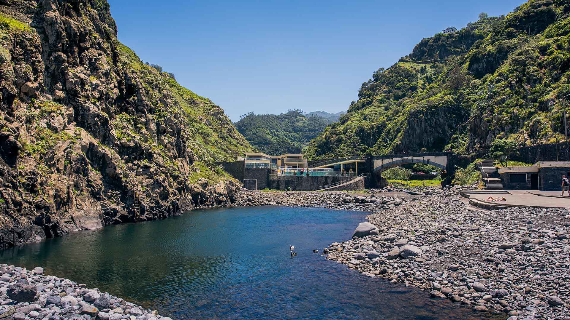 Lago en una playa de calhau junto a la montaña en Madeira.