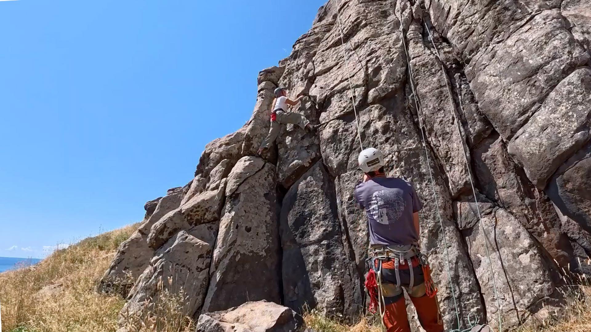 Mulher a praticar escalada equipada com capacete e arnês.