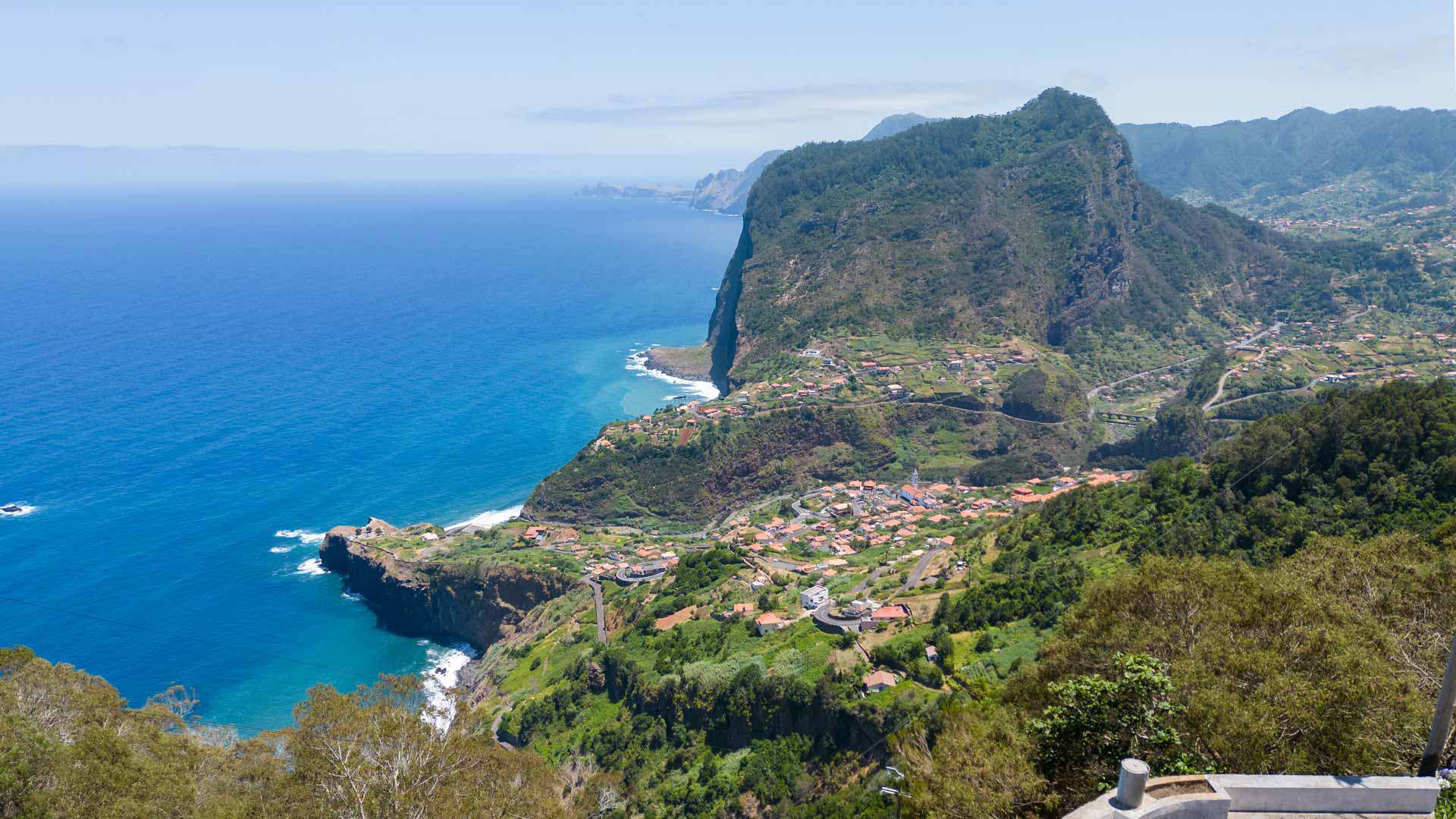 Green valleys with houses, mountains, and sea view.