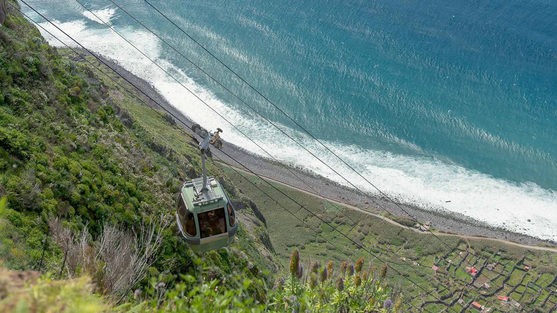 Cabine de teleférico sobre montanha com vista para o mar na Madeira.