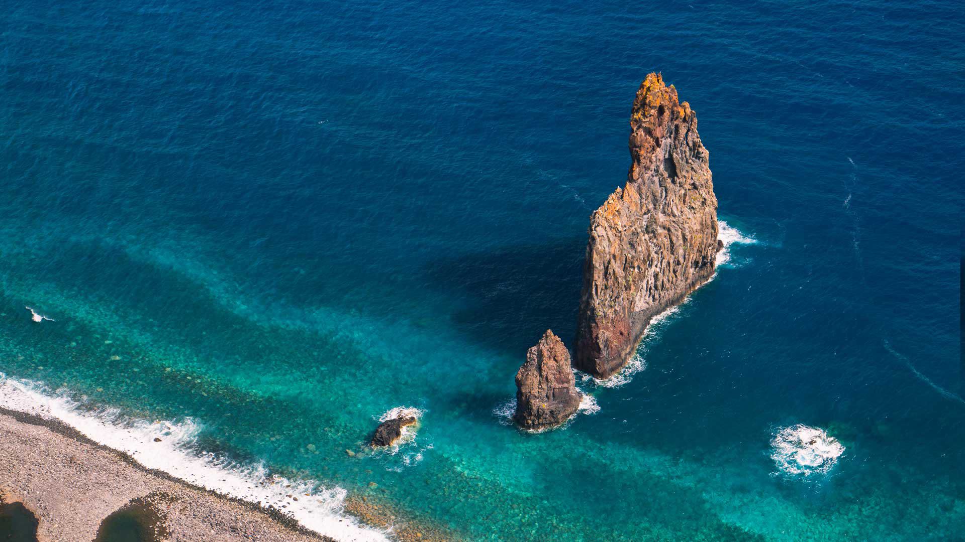 Formación rocosa en el mar junto a la costa con agua azul en Madeira.