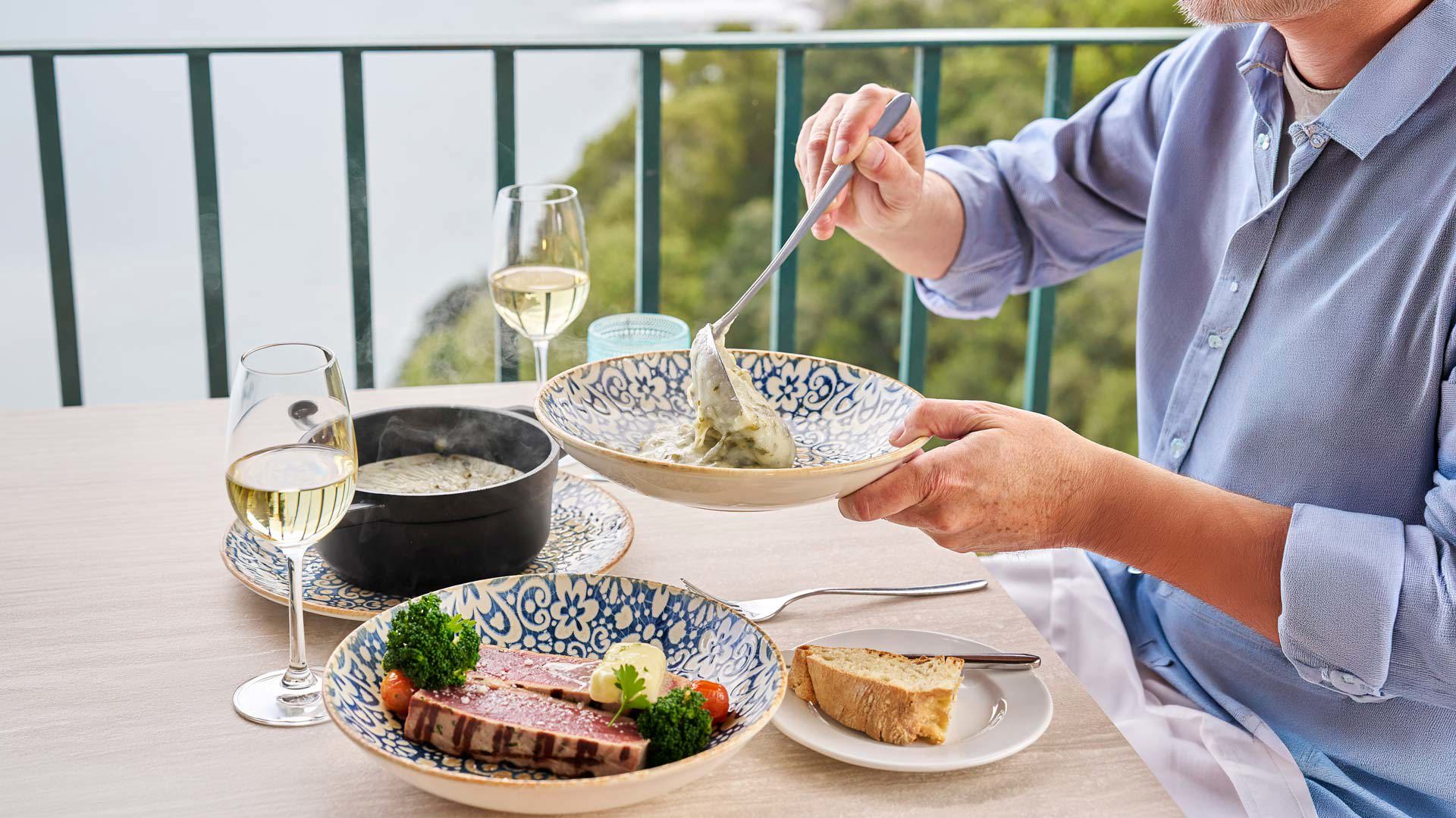Meal with tuna steak, boiled maize and white wine served at the table.