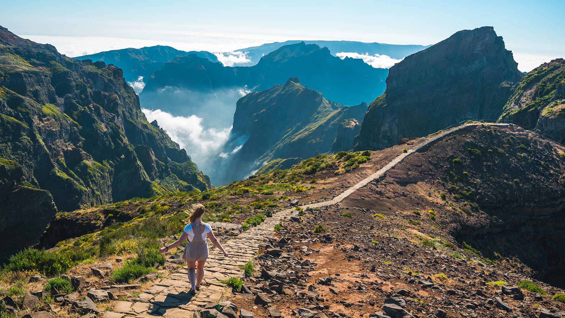 Woman walking on a trail in the mountains with clouds in Madeira.
