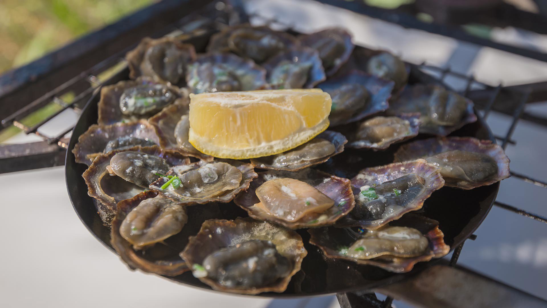 Patelles grillées servies dans leur poêle avec citron.