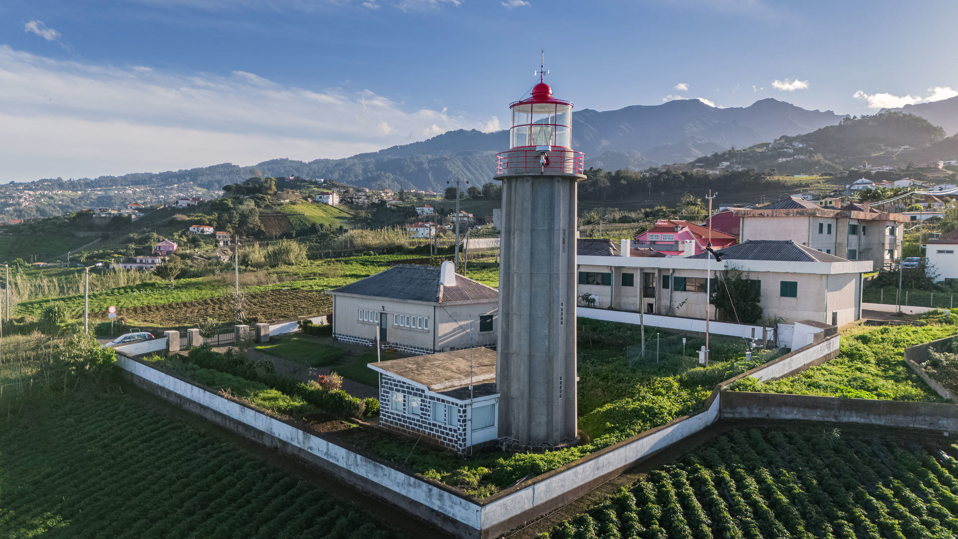 Faro junto a casas y terrenos cultivados en Madeira.
