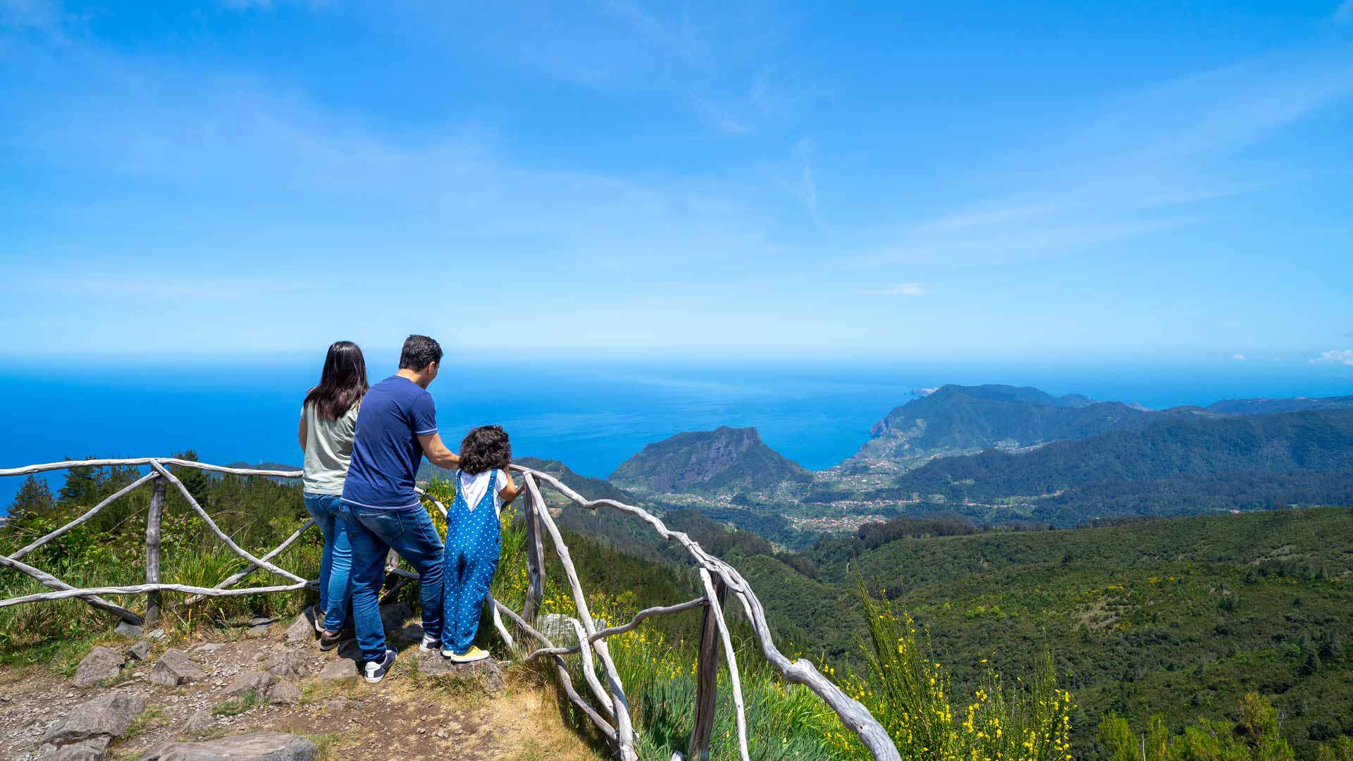 Familie an einem Aussichtspunkt auf Madeira mit Berg- und Meerblick.