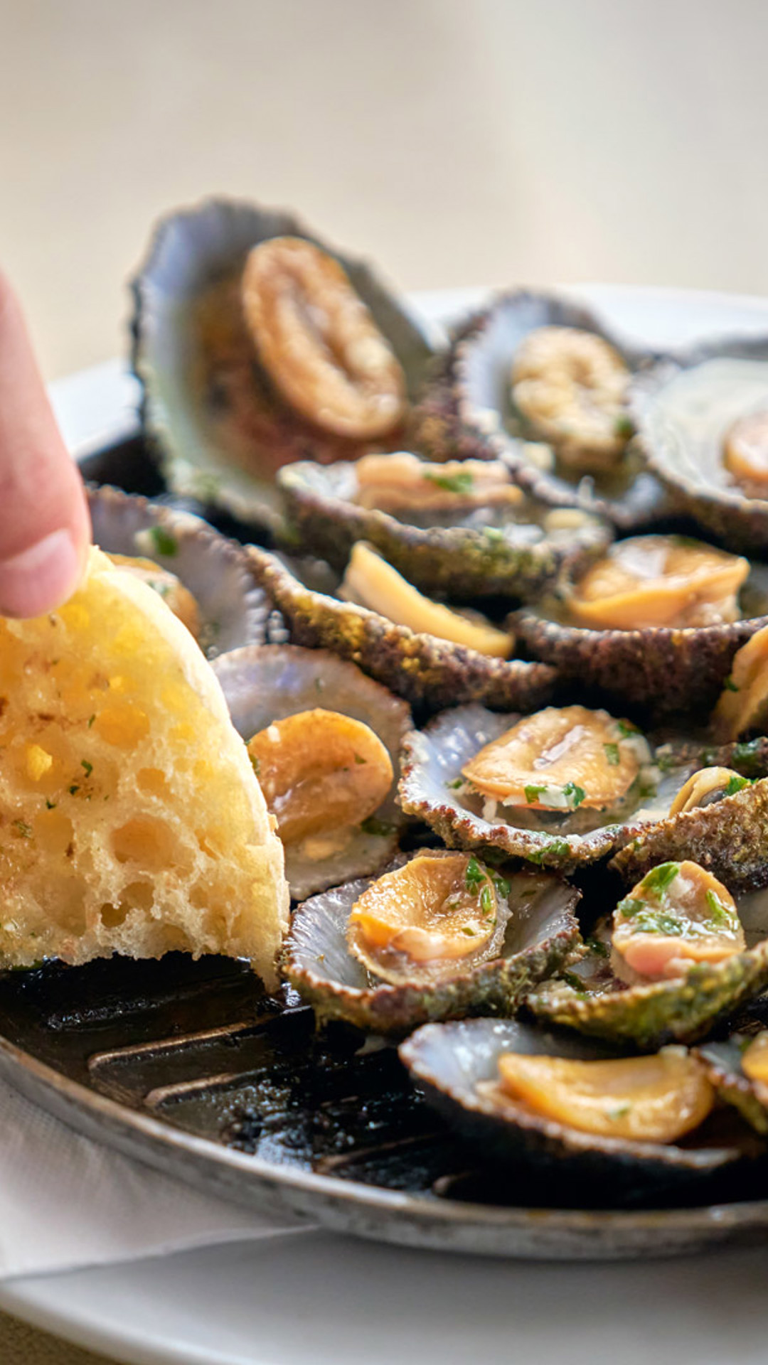 Personne trempant du bolo do caco dans la sauce de la poêle des patelles.