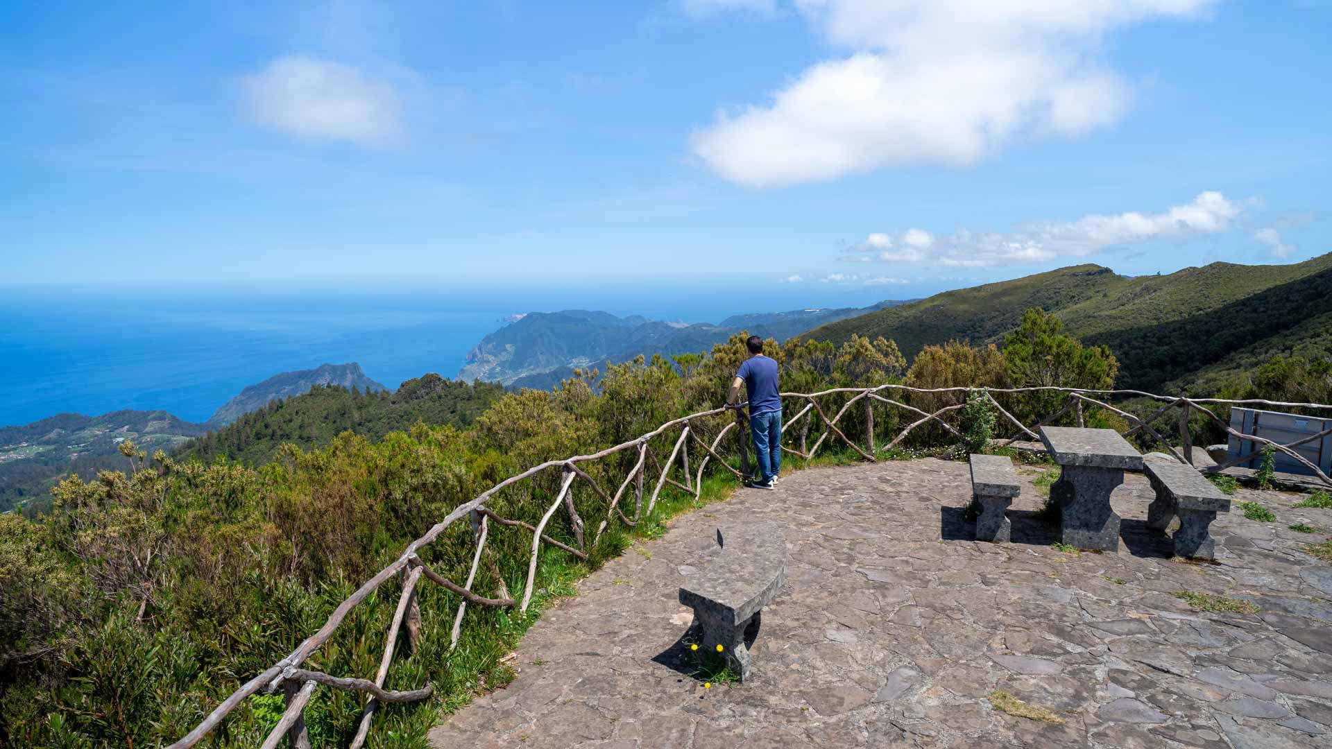 Mirador con bancos de piedra y vista a montañas y mar.