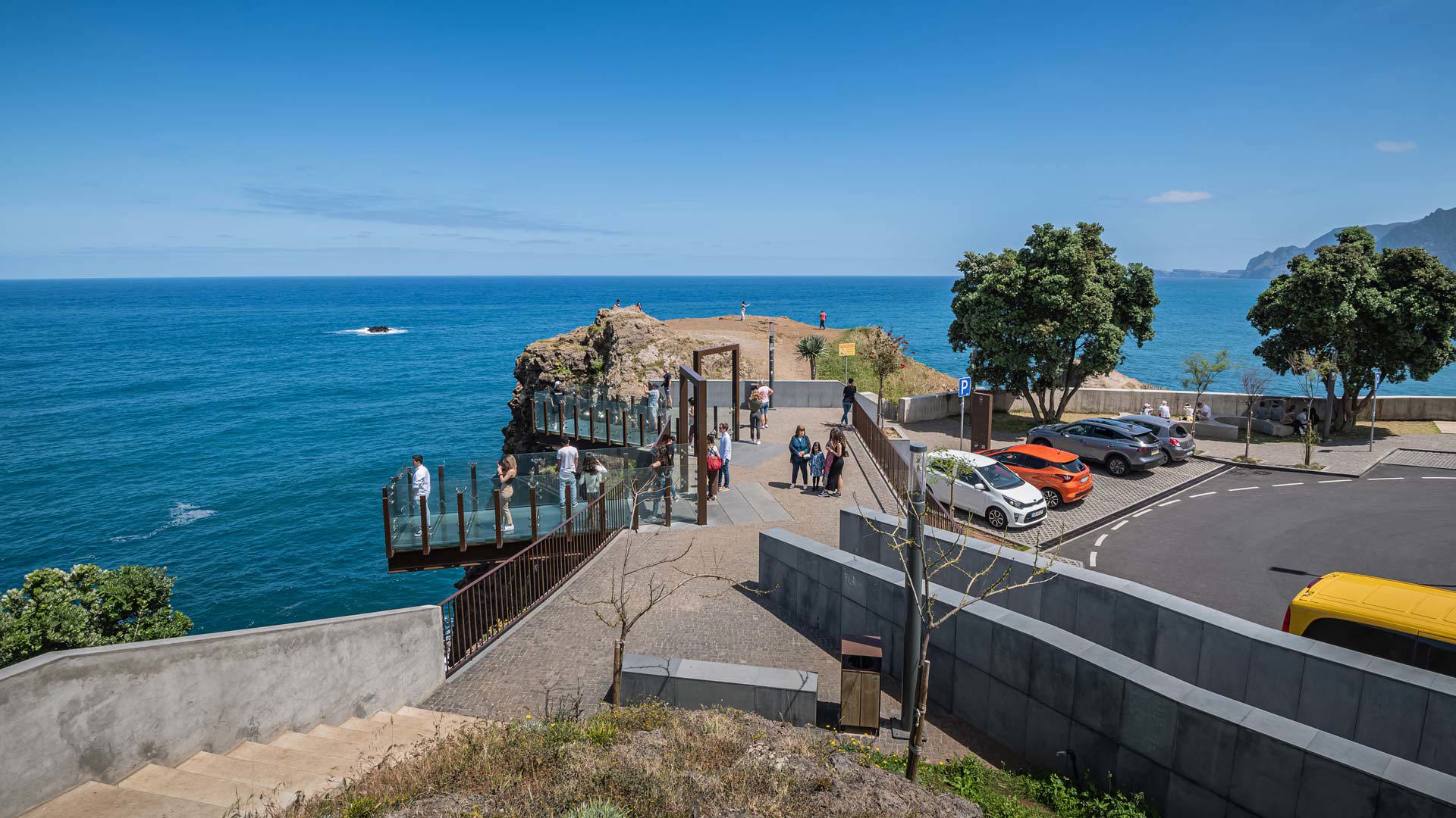 Mirador de vidrio y cemento con personas en una ladera en Madeira.