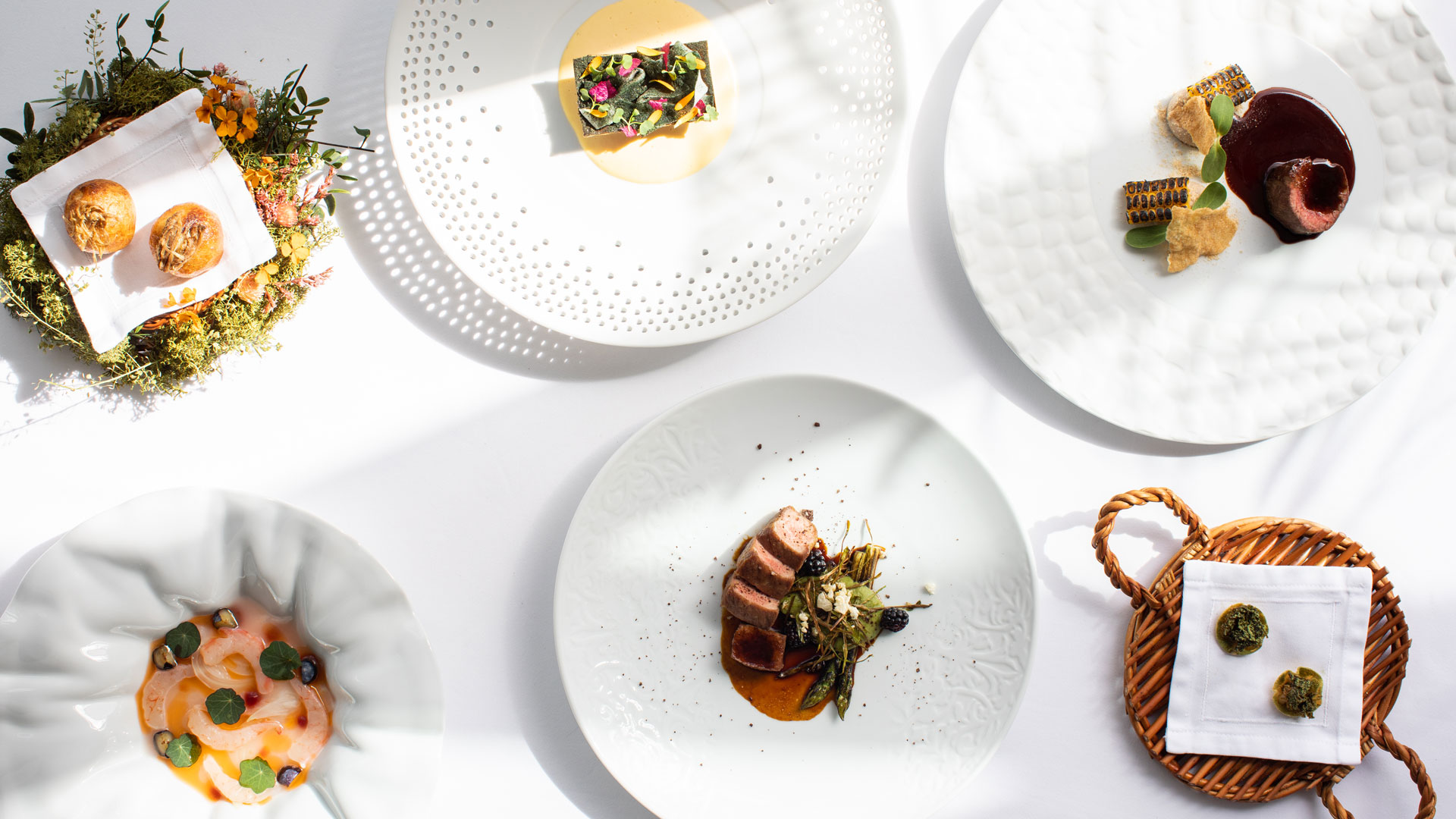 Tisch mit mehreren angerichteten Gerichten in zeitgenössischer Gourmetküche.