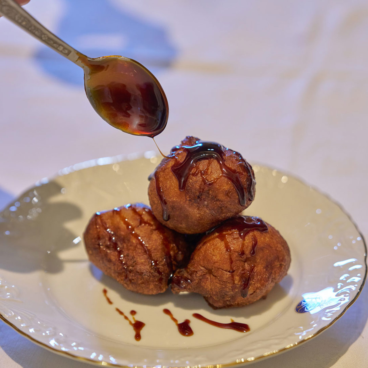Plate with malassadas topped with sugarcane honey, a traditional sweet from Madeira Island.