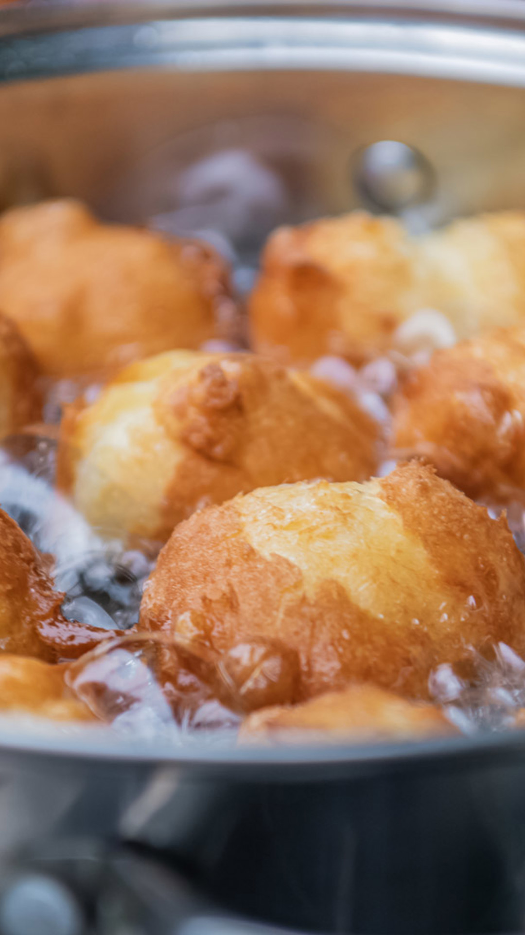 Malassadas a fritar numa panela com óleo quente.