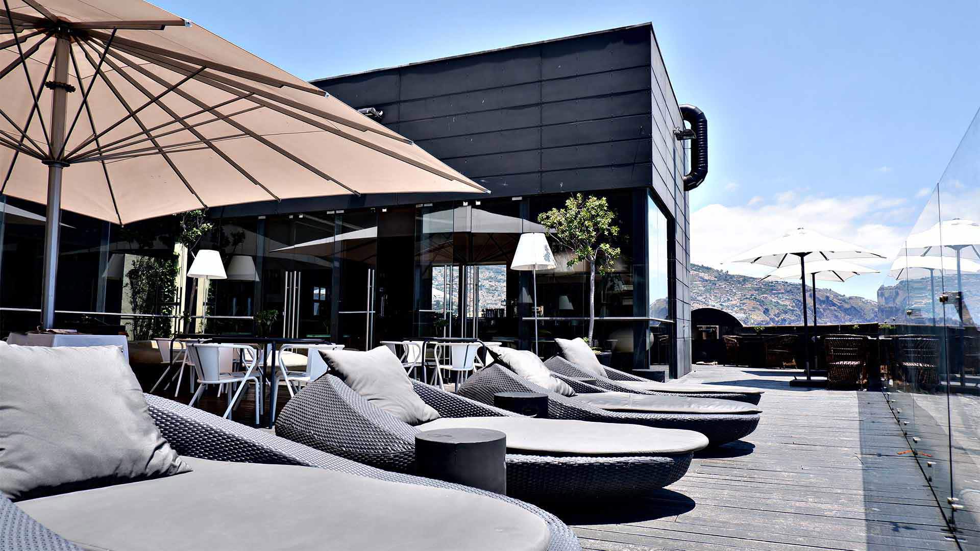 Espreguiçadeiras sob chapéu de sol ao sol.