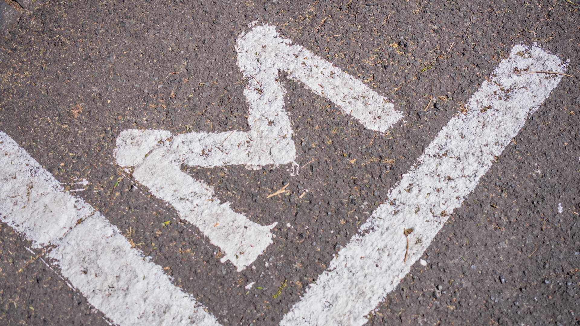 Straße mit weißer Linie und Buchstabe M auf dem Asphalt markiert.