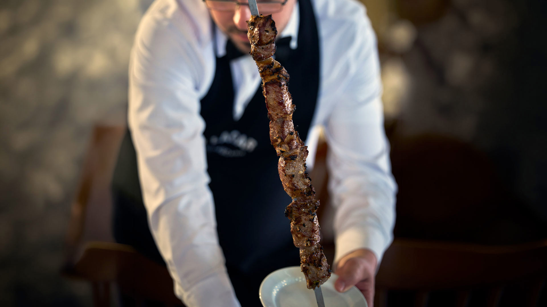 Persona sirviendo espetada de Madeira durante una comida en un restaurante de la isla de Madeira.