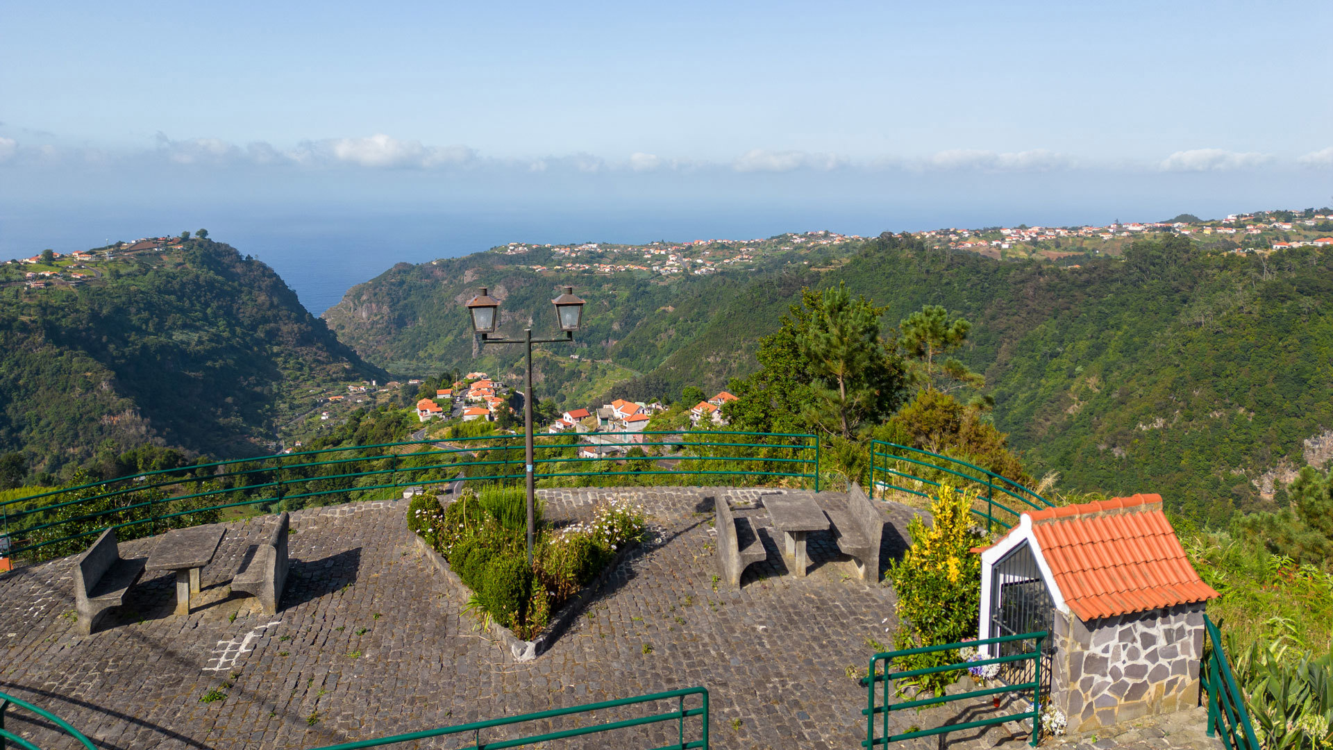 Mesas de picnic con vista a montañas y casa de piedra en Madeira.