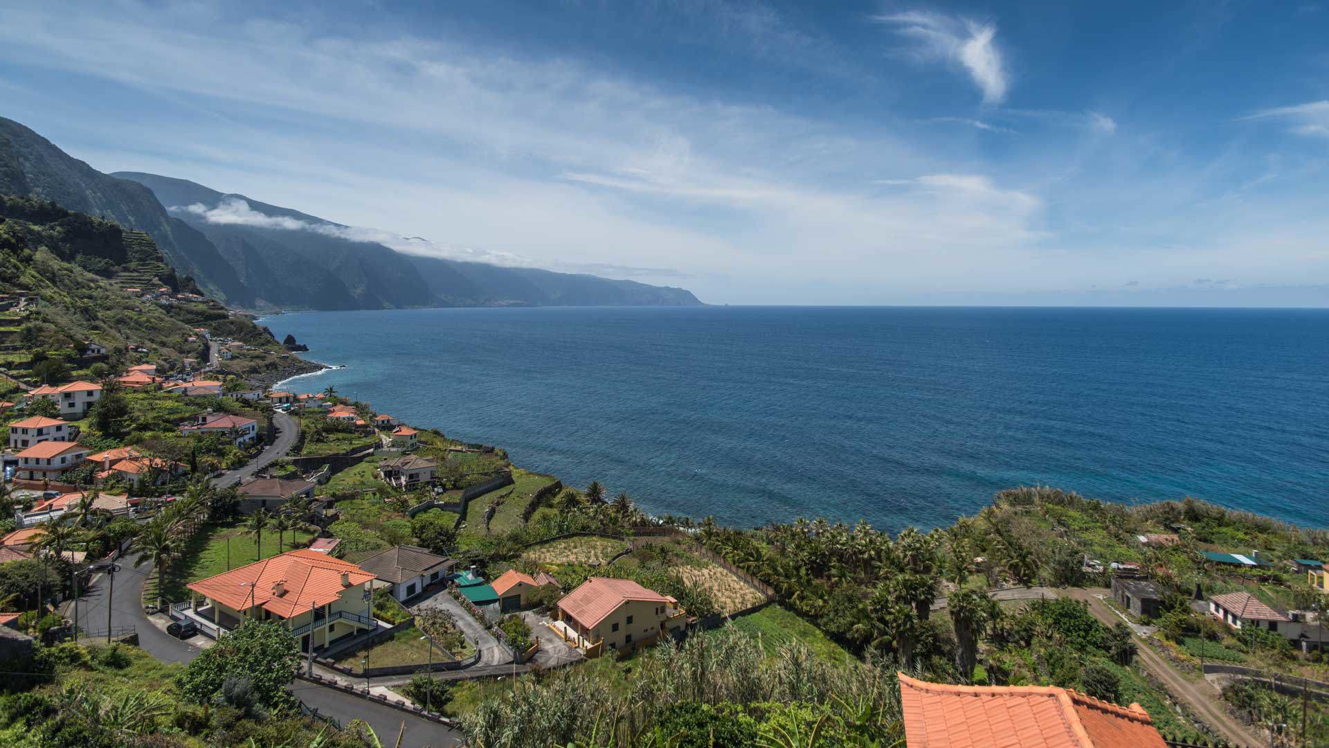 Maisons au bord de la mer avec montagnes en arrière-plan.