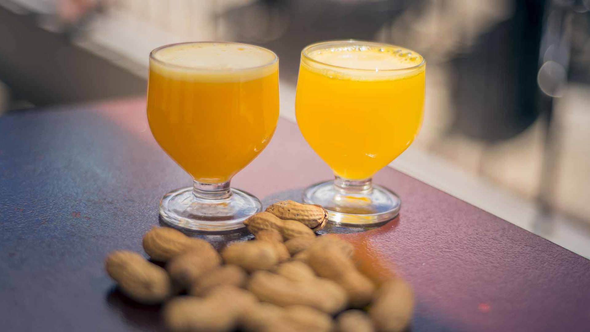 Dos vasos de poncha tradicional servidos con cacahuetes sobre un mostrador en la isla de Madeira.