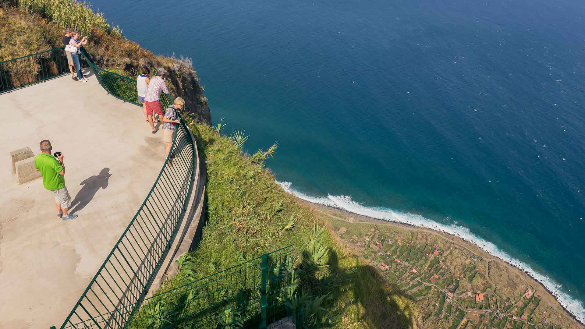 Personen am Aussichtspunkt, die das Meer und den Hang auf Madeira beobachten.