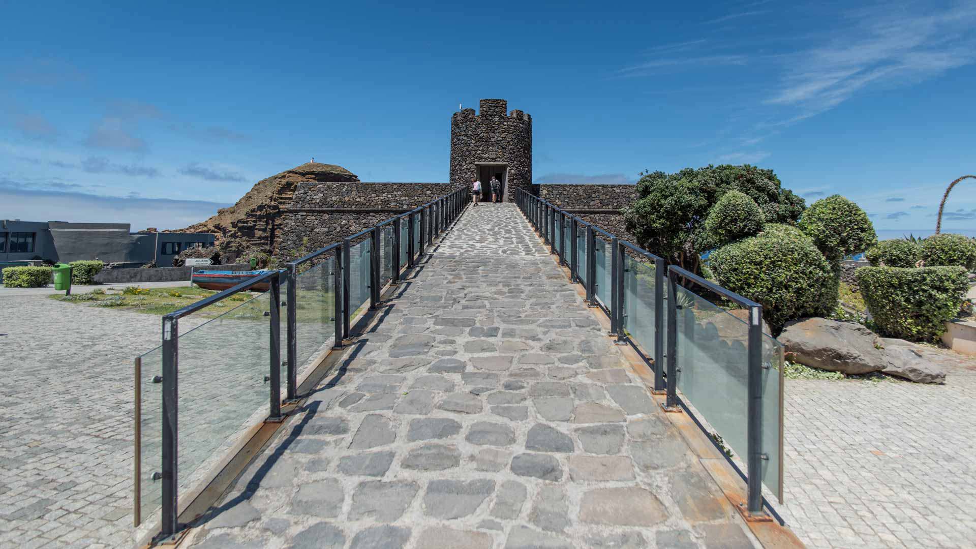 Bridge with glass balconies facing a stone fort.