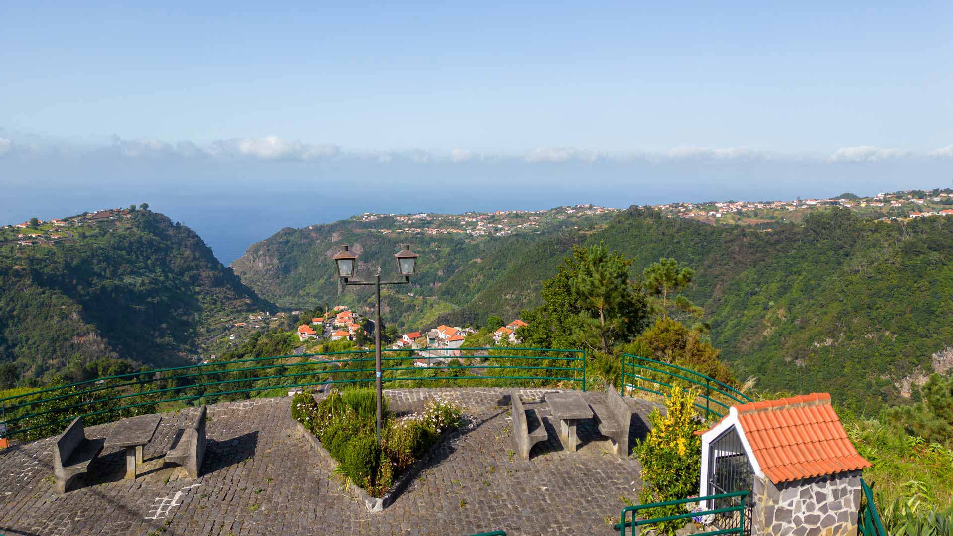Mesas de picnic con vista a montañas y casa de piedra en Madeira.