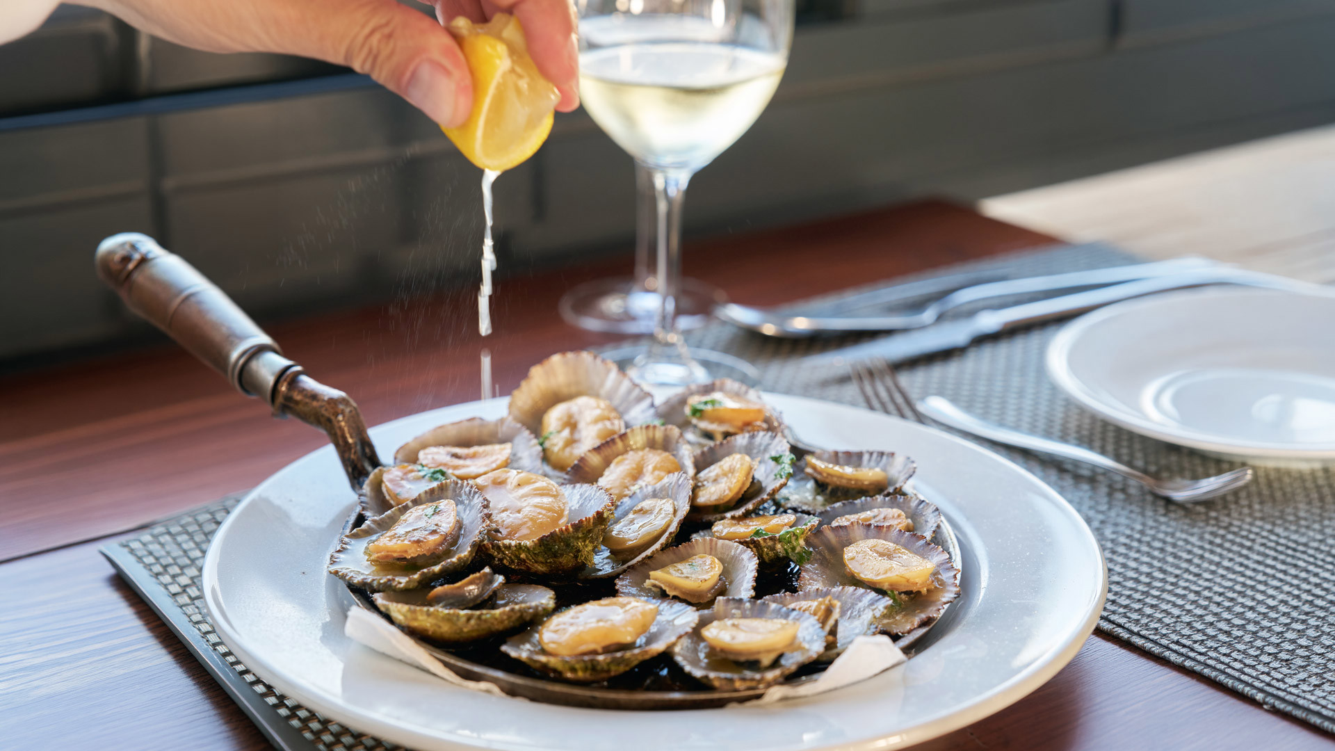 Personne pressant du citron sur une portion de patelles de l’île de Madère.