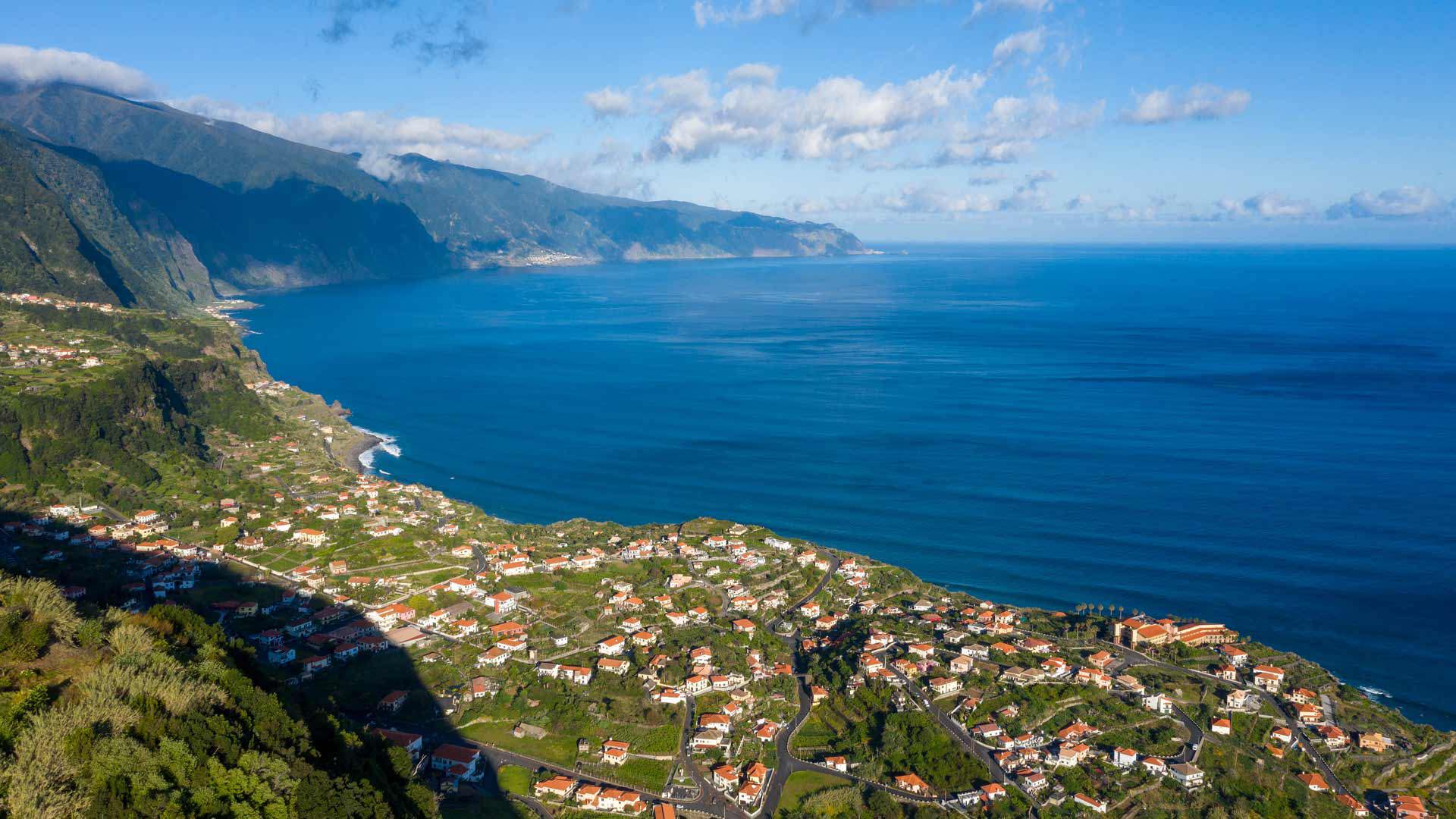 Houses in a valley with sea and mountain in the background.