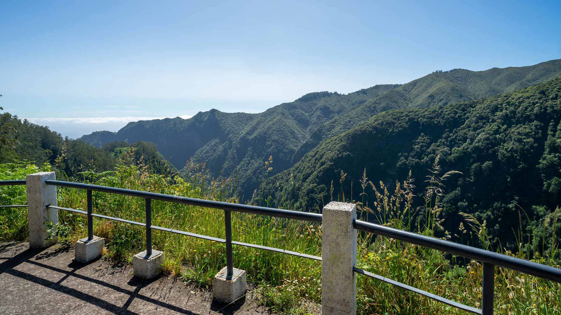Miradouro com vista para montanhas e vegetação verde.