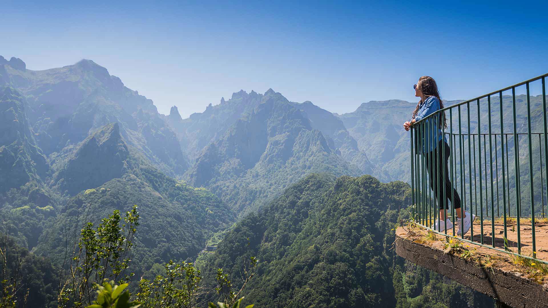 Mulher num miradouro com vista para a montanha.