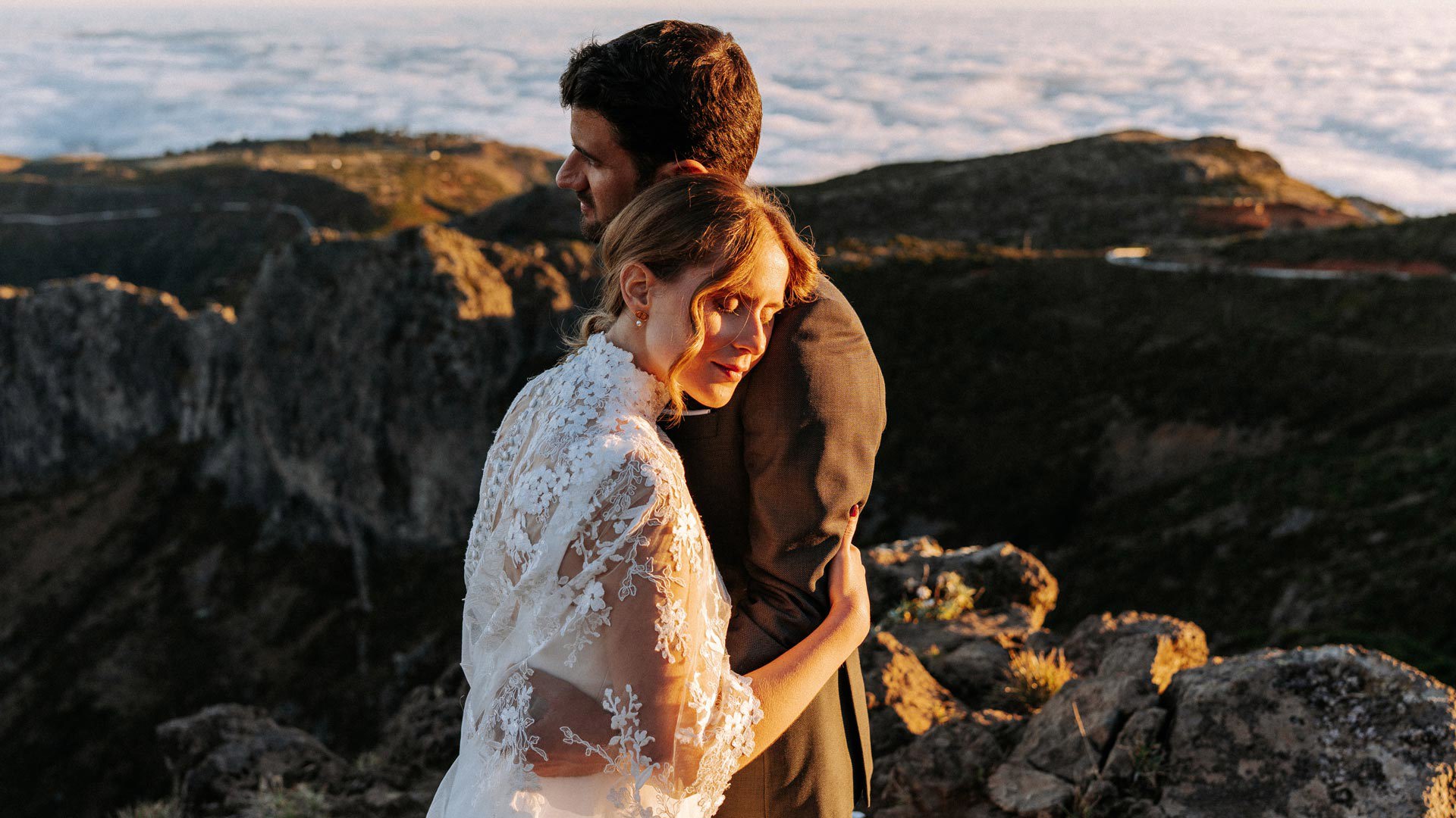 Paar in Hochzeitskleidung in den Bergen über den Wolken, umarmt. 