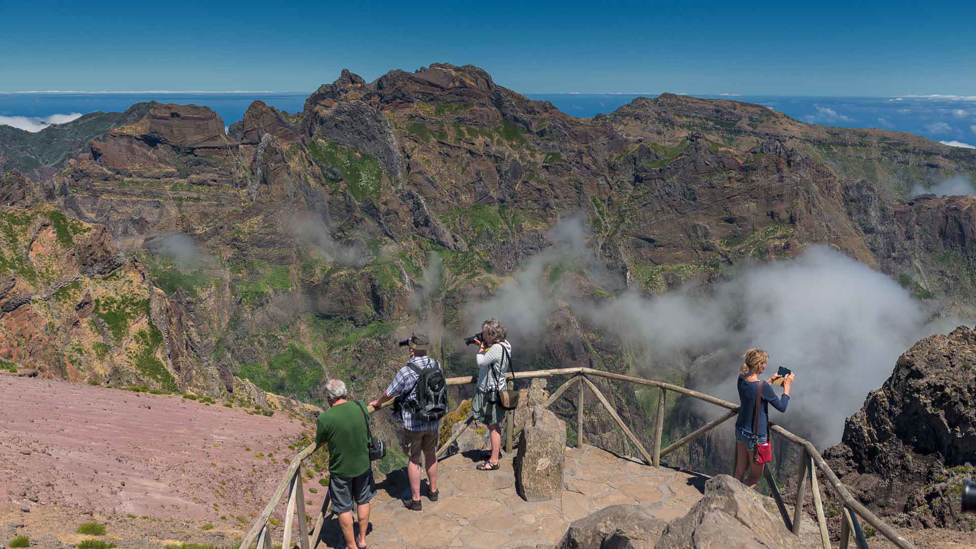 Cuatro personas sacando fotos en un mirador con vista a montañas en Madeira.