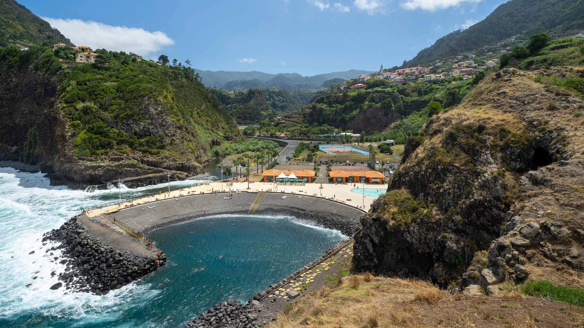 Playa de callao con olas, montañas y casas al fondo en Madeira.