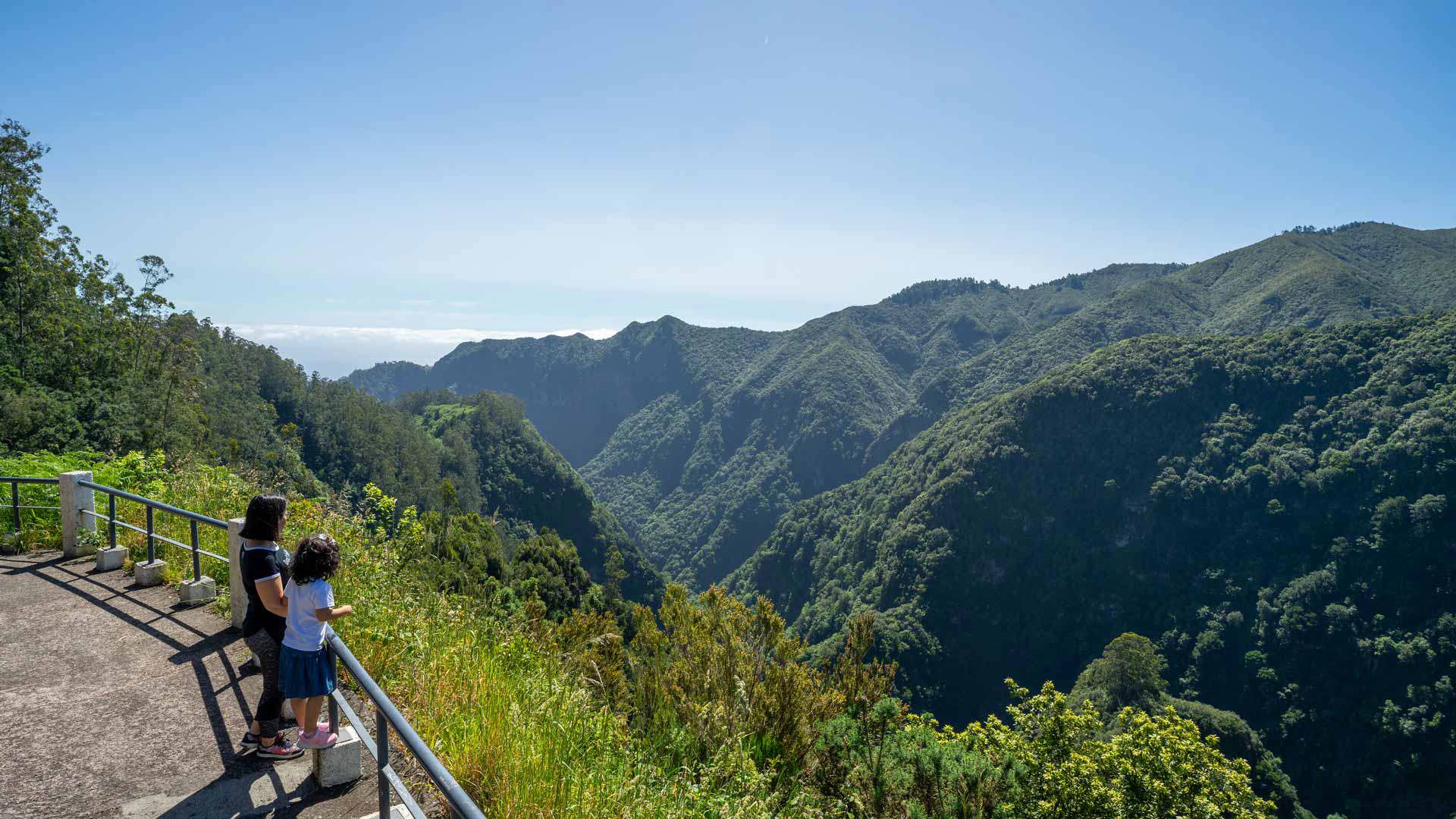 Duas pessoas em miradouro com vegetação verde na Madeira.