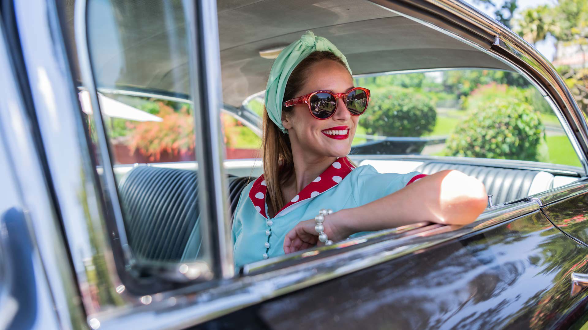 Femme assise à l’intérieur d’une voiture classique.