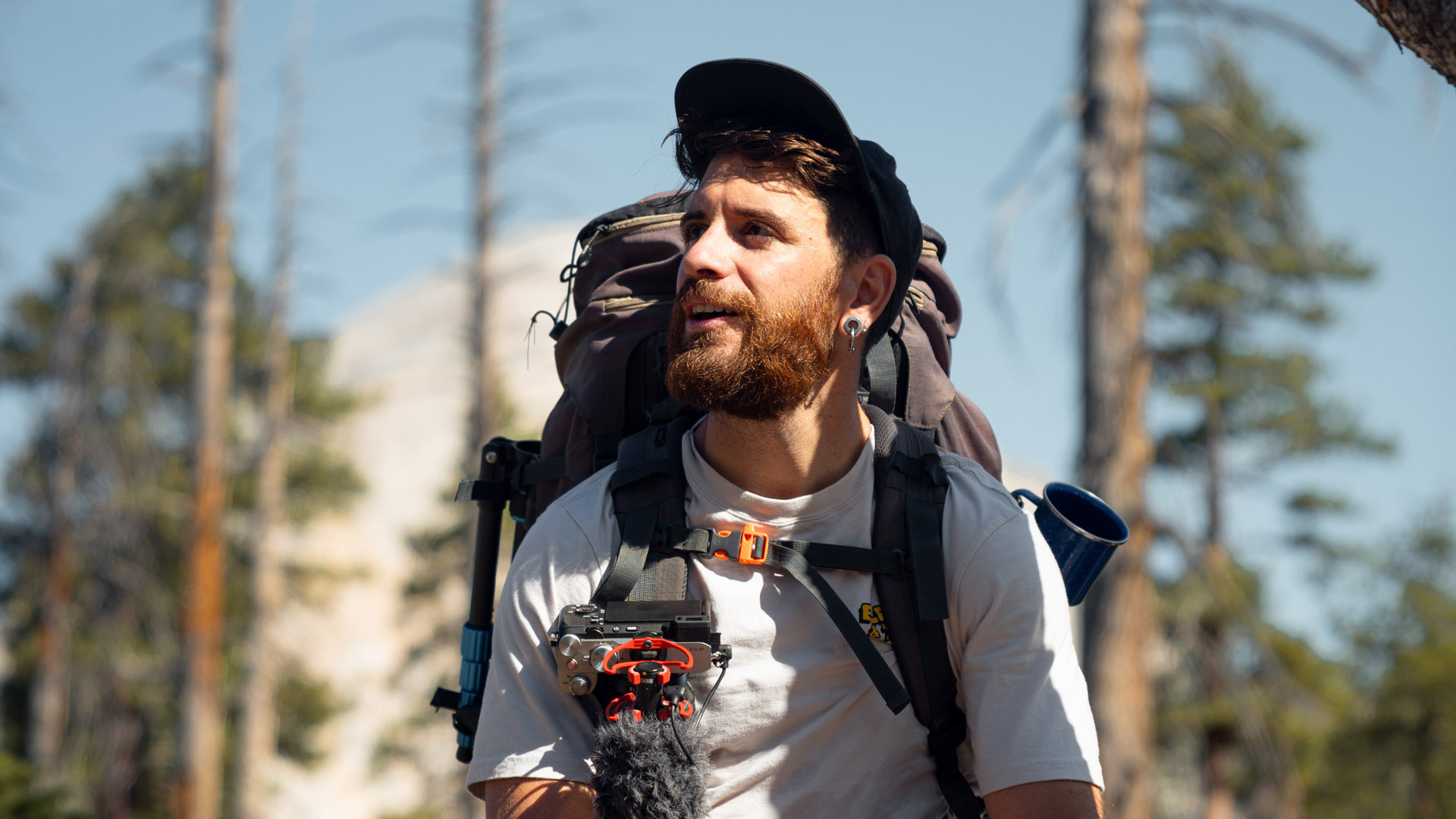 Mann mit Mütze und Rucksack lächelt.