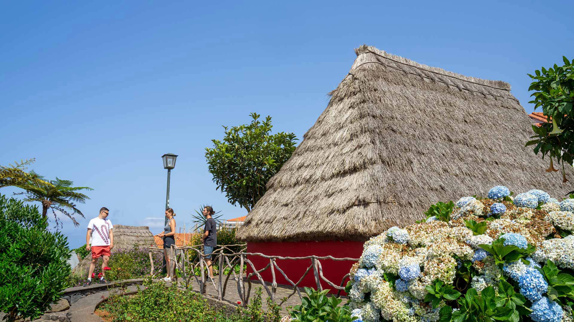 Typisches Haus auf Madeira mit Blumen und Menschen rundherum.