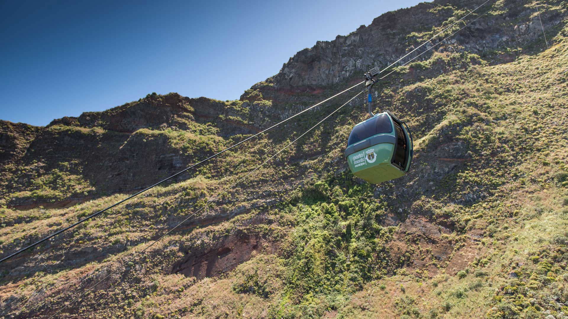 Cabine de teleférico sobrevoa encosta de montanha.