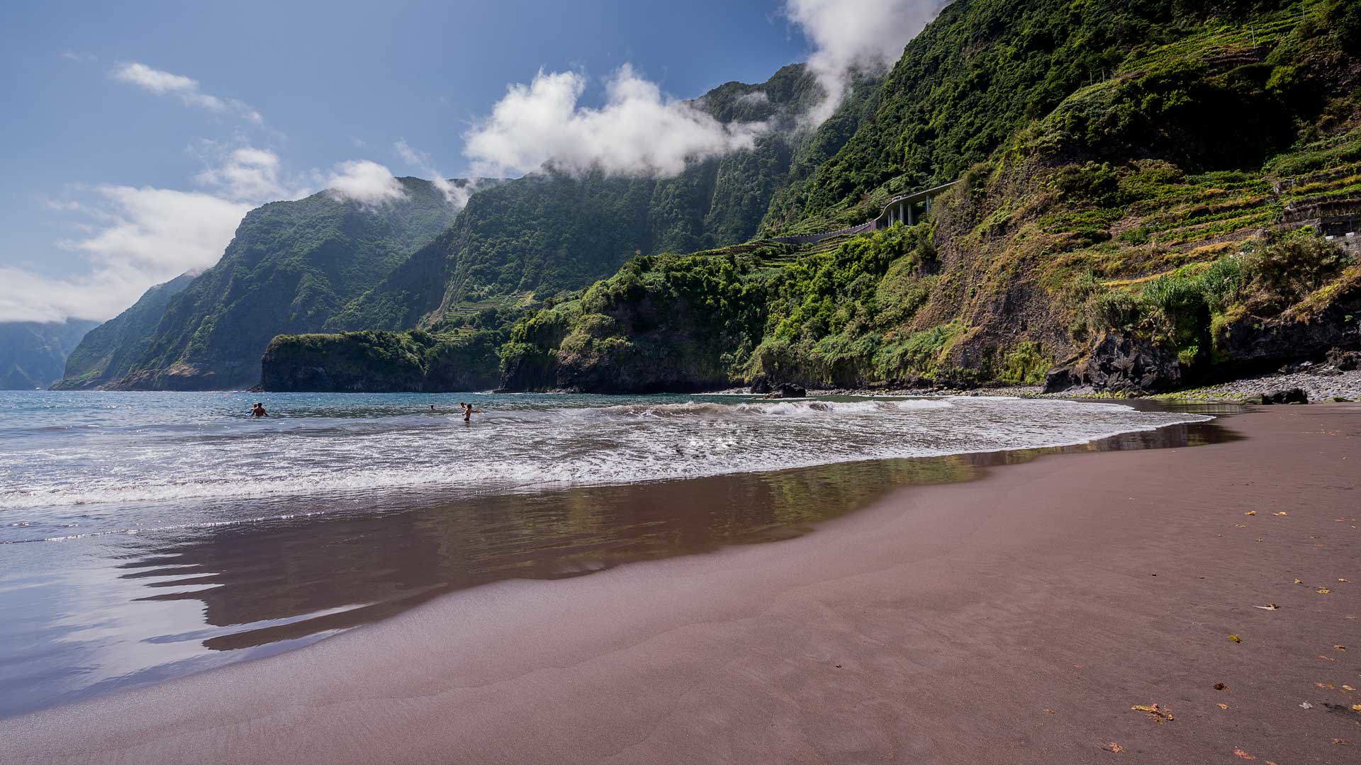 Plage de sable noir avec montagne et nature environnante à Madère.