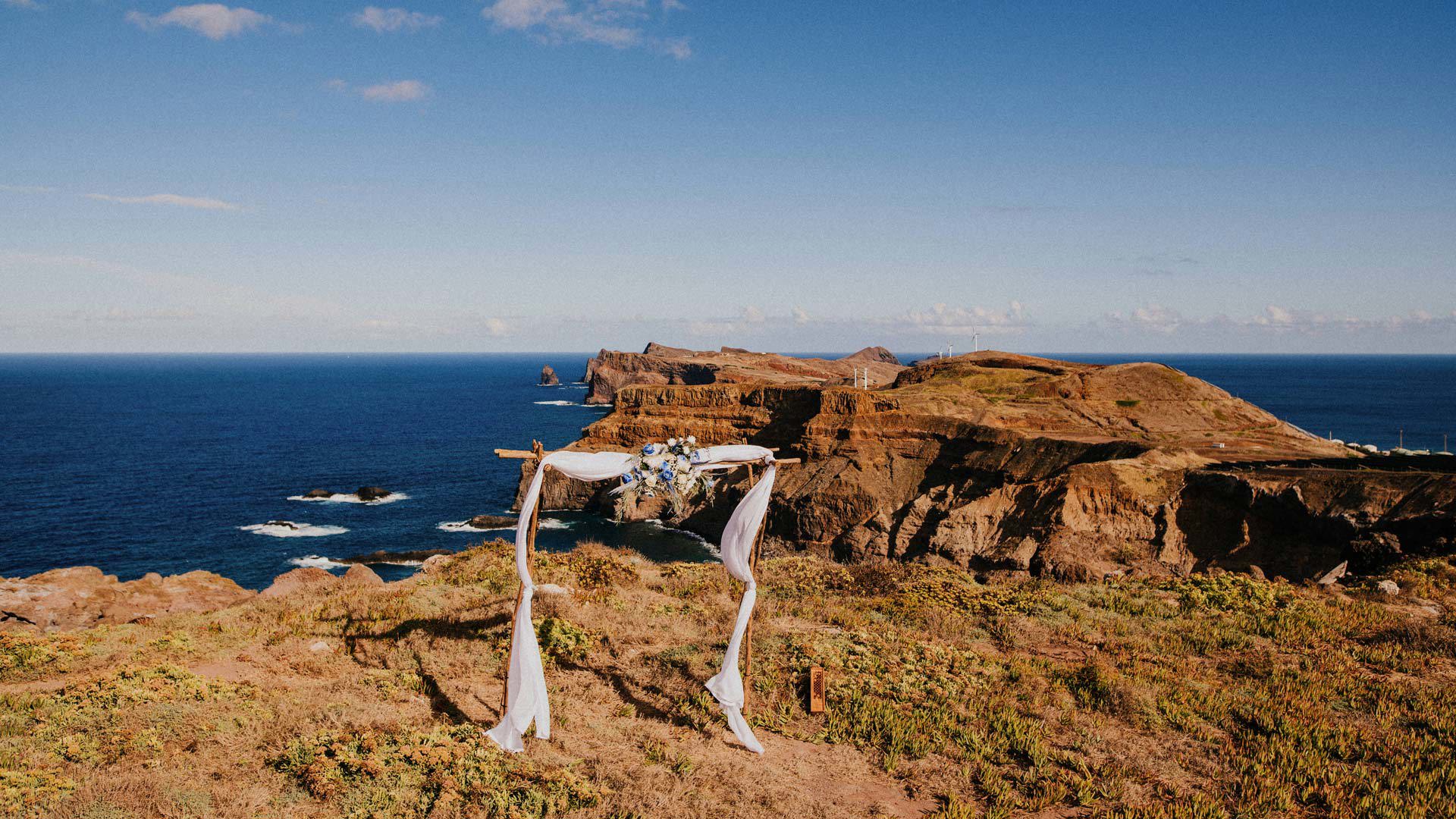Arco de cerimónia de casamento com vista para o mar e as montanhas.