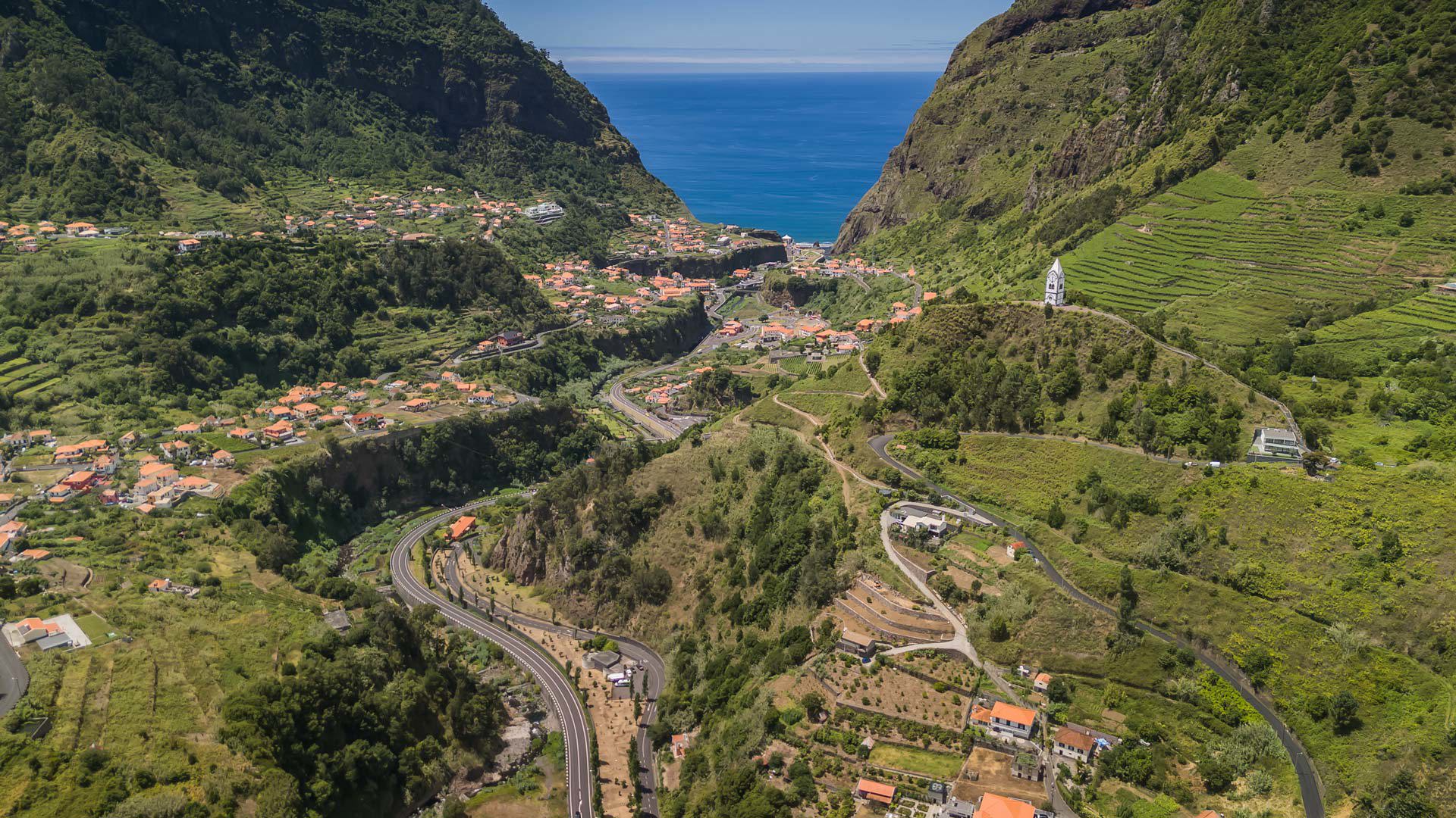 Maisons et routes dans une vallée entourée de nature.