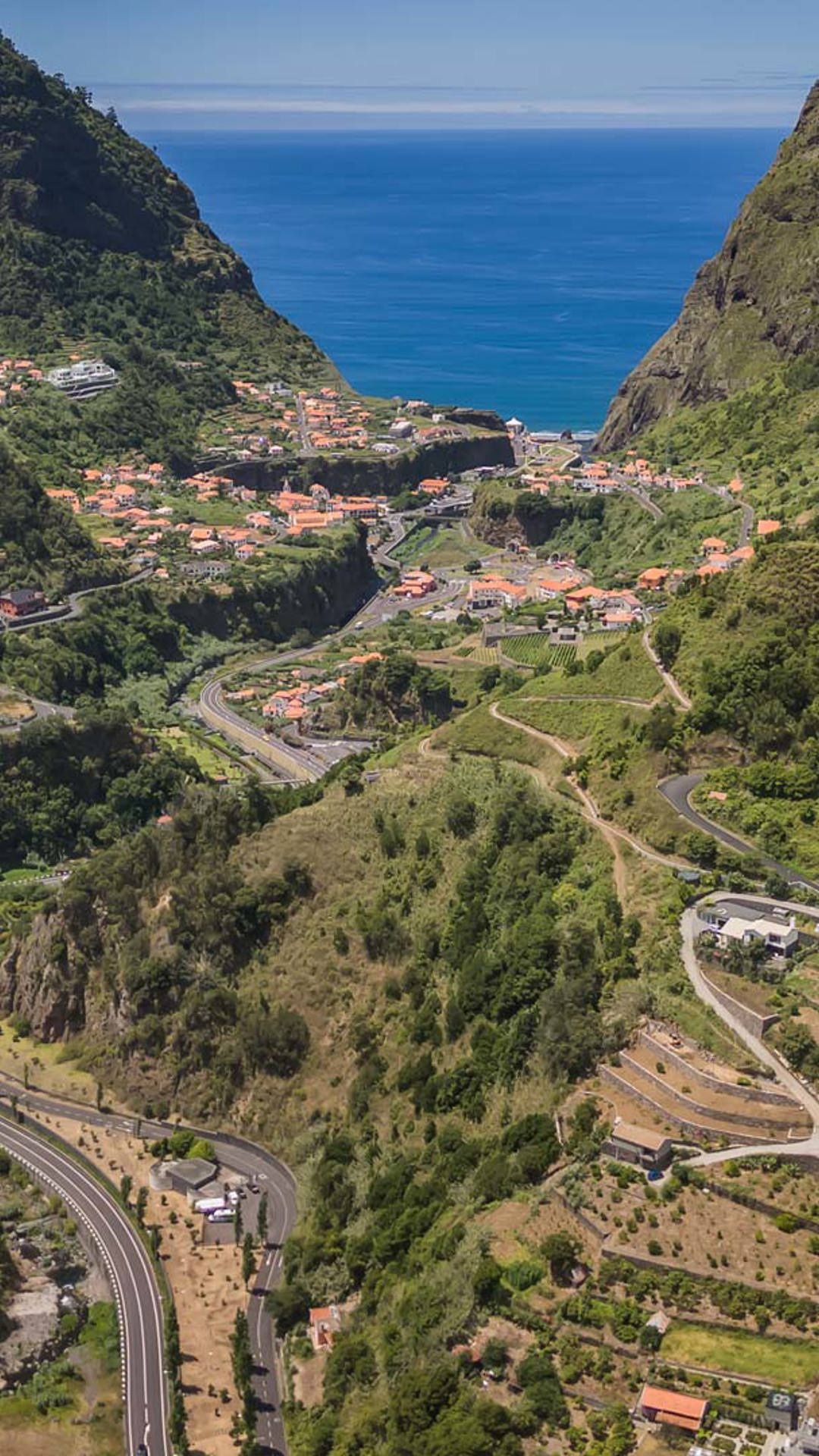 Casas e estradas num vale rodeado de natureza.
