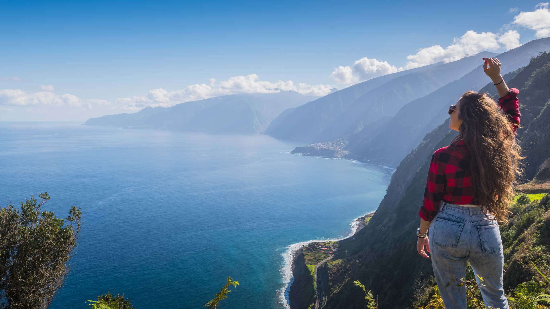 Frau am Aussichtspunkt, die Küste und das Meer auf Madeira beobachtet.