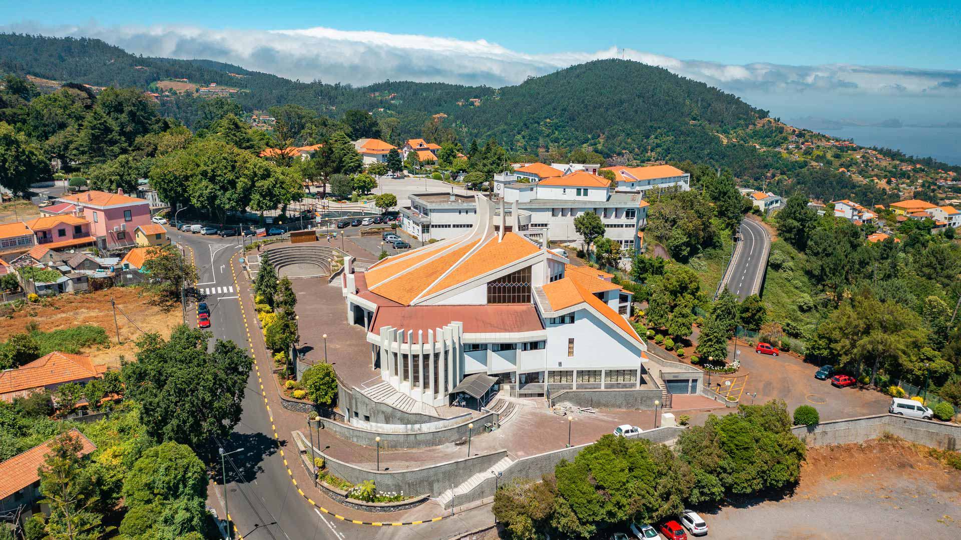 Exterior de iglesia en un pueblo con una montaña al fondo.