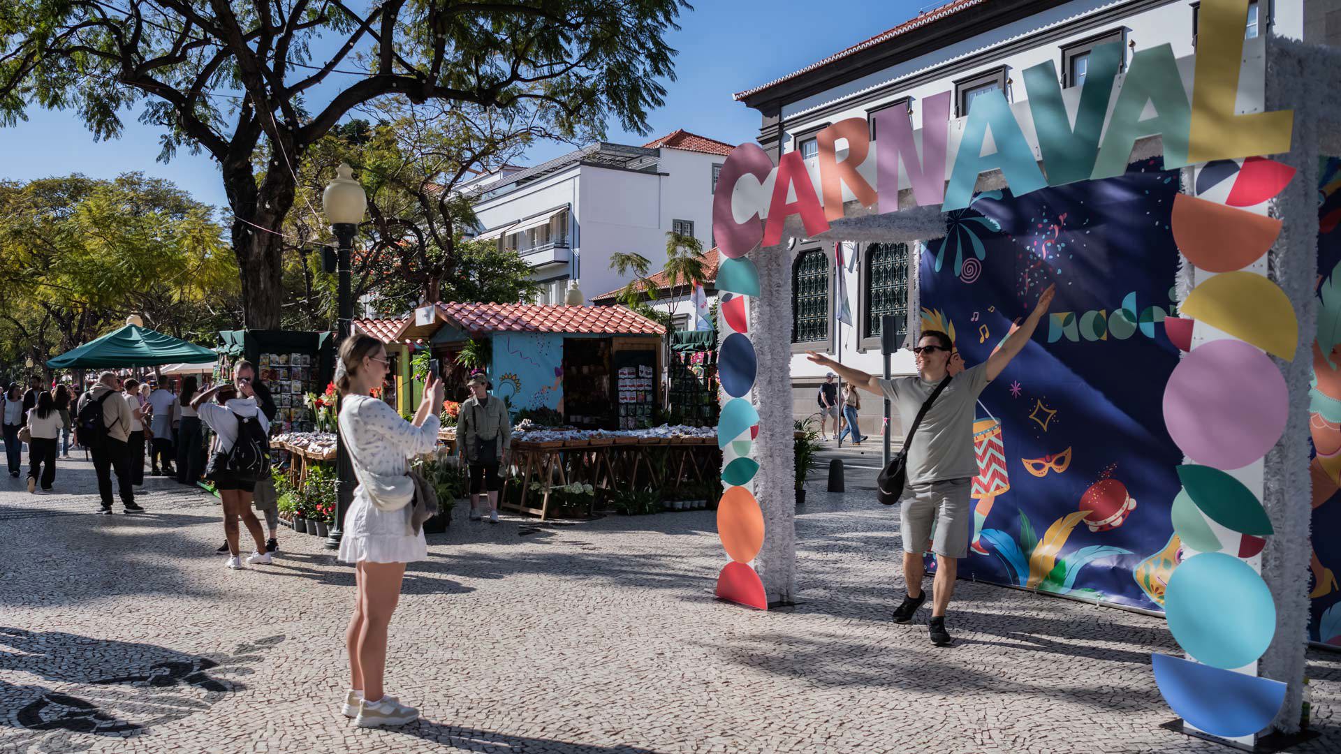 Woman taking photos of a man among Carnival decorations in Madeira.
