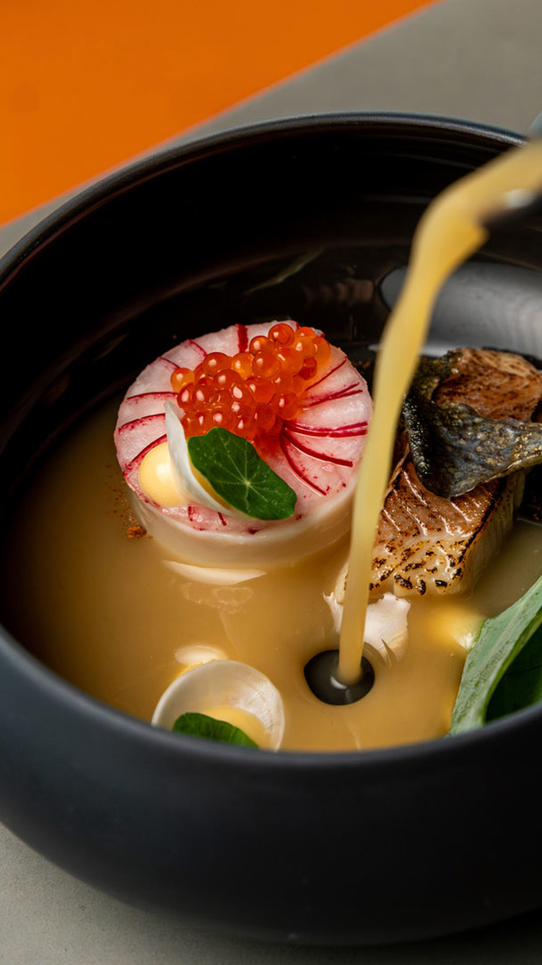 Hand beim Anrichten eines Gerichts im Stil der zeitgenössischen Küche.