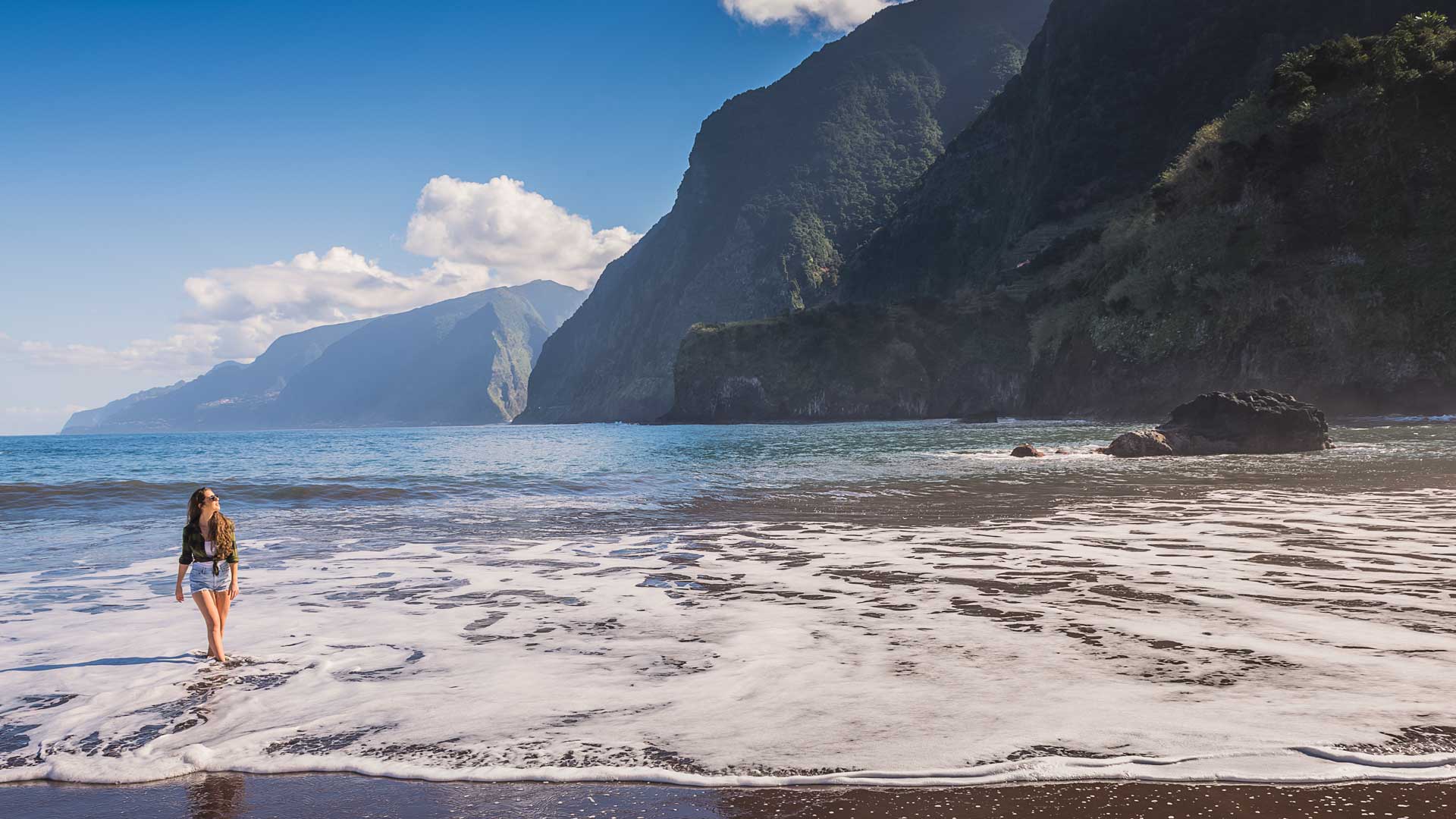 Mujer junto al mar con vista al mar y montañas al fondo en Madeira.