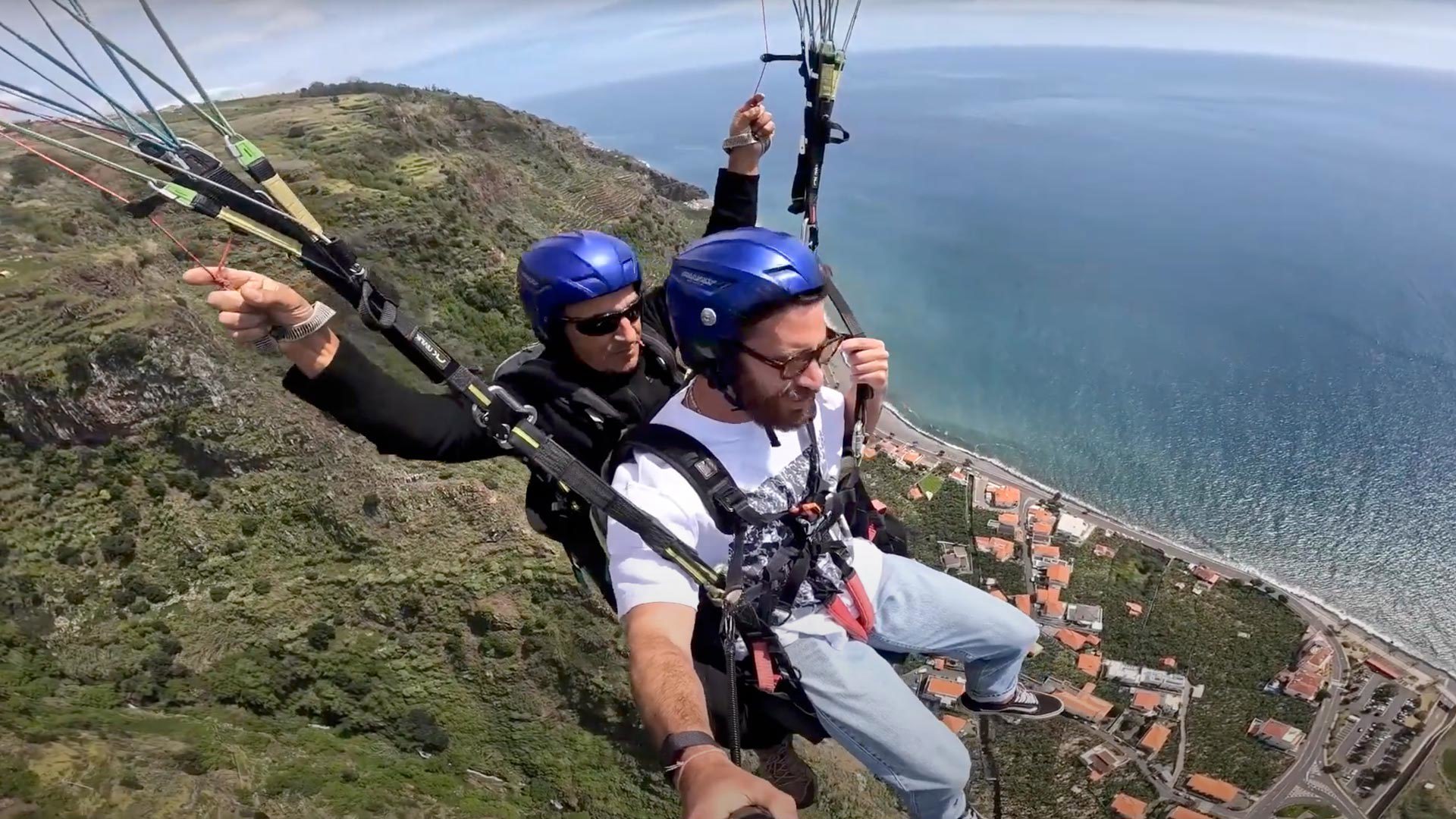 Mann beim Gleitschirmfliegen am Himmel, mit Helm.