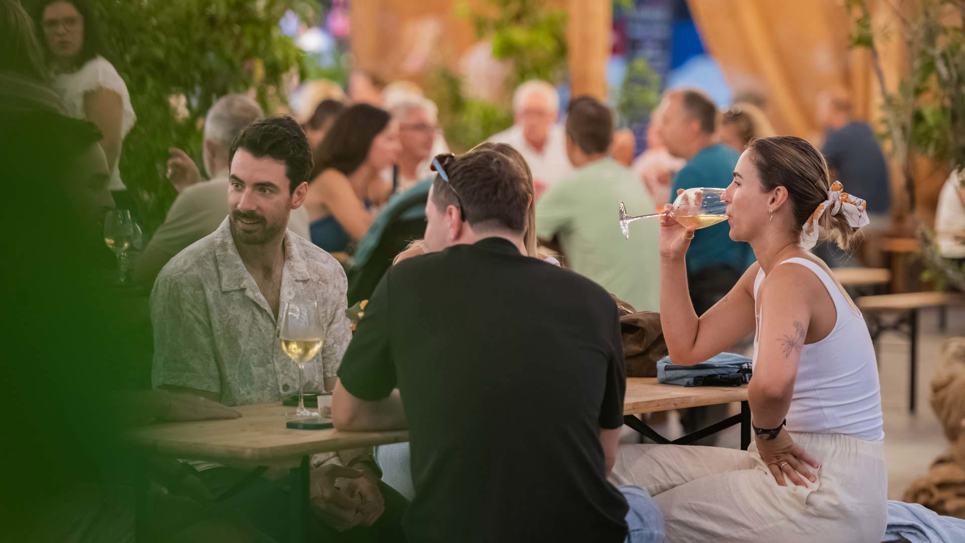 Friends socializing at the Wine Lounge during the Wine Festival at a table.